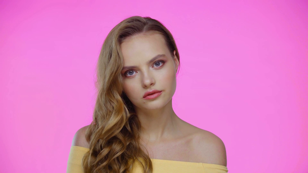Junge Frau blickt isoliert auf rosa Kamera - Filmmaterial, Video