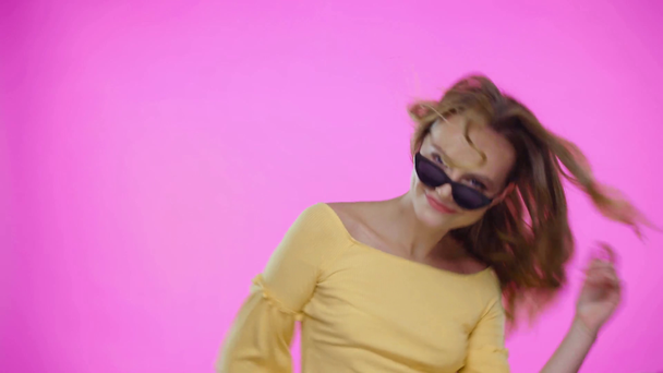 Молода жінка в сонцезахисних окулярах танцює ізольовано на рожевому
 - Кадри, відео
