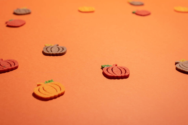 Gefilzte Kürbisse auf orangefarbenem Schreibtisch in Großaufnahme mit Kopierraum. Halloween-Ästhetik Hintergrund in buntem Karton leer zum Hinzufügen von Text oder Design - Foto, Bild
