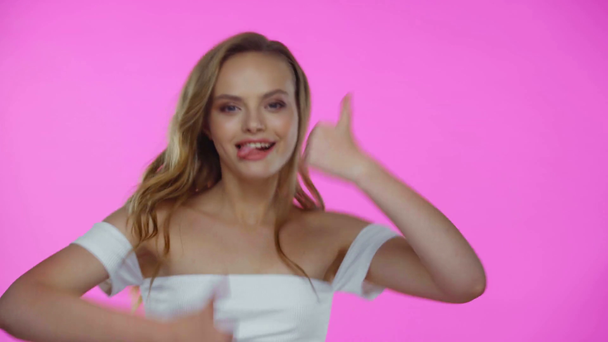 Fiatal nő mutatja hüvelykujját felfelé, és kinyújtja nyelv elszigetelt rózsaszín - Felvétel, videó