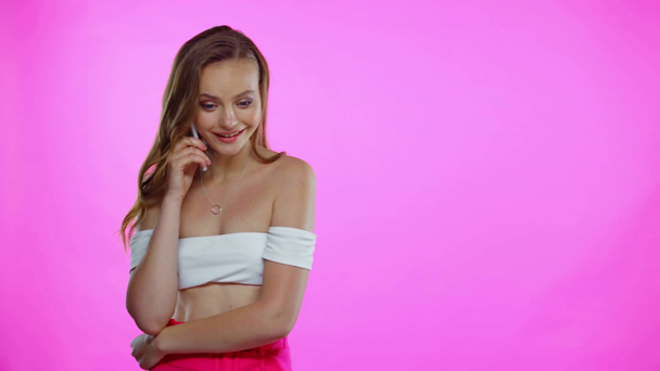 Mujer joven hablando por teléfono, mostrando un gesto de saludo aislado en rosa - Metraje, vídeo