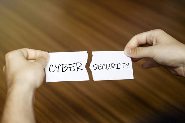 zerrissenes Papier mit Text Cyber Security in männlichen Händen auf Holzhintergrund - Foto, Bild