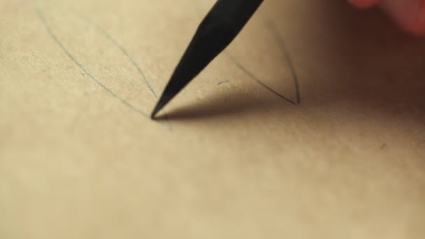 Desenho de mão de artista com um lápis de madeira de grafite em papel kraft. Fecha, macro. - Filmagem, Vídeo
