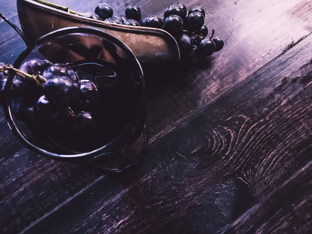 Ein Glas Wein und Trauben auf einem Holztisch - Foto, Bild