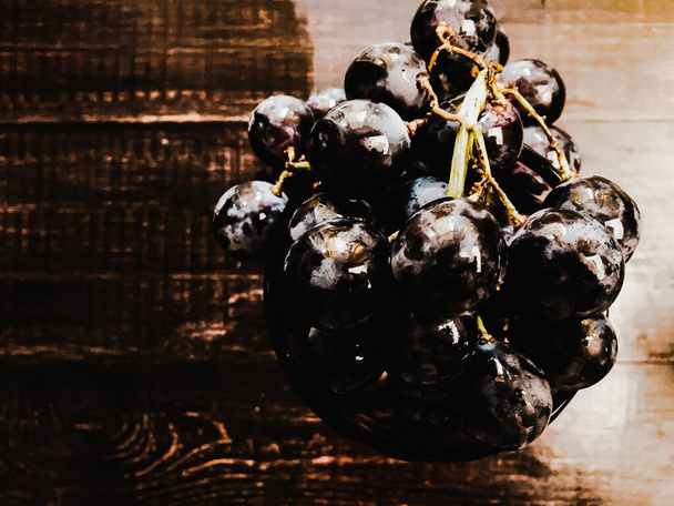 Een glas wijn en druiven erin op een houten tafel - Foto, afbeelding