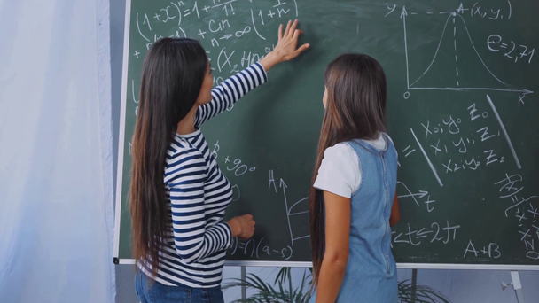 mother explaining math to daughter near chalkboard  - Footage, Video