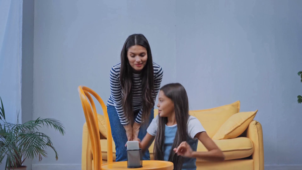 lapsi ja äiti istuu sohvalla ja tanssii tehdessään videon älypuhelimella - Materiaali, video