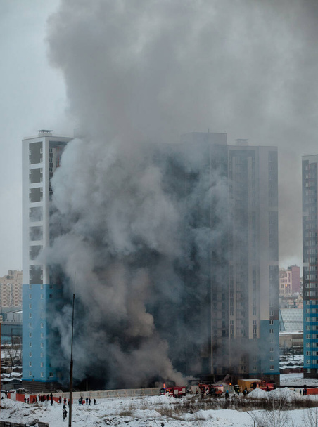 Brand in een residentieel hoogbouw. Veel rook- en brandweerwagens - Foto, afbeelding