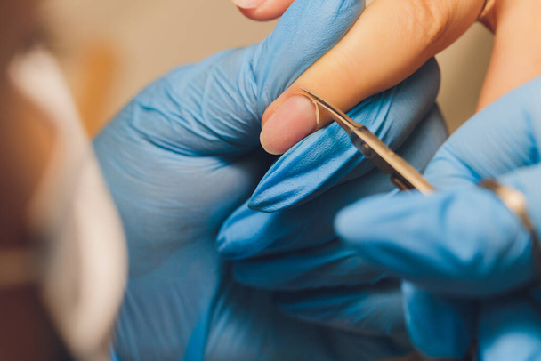 Nail care at a beauty salon. Manicurist removing edges with scissors. Let your hands look gorgeous. - Fotó, kép