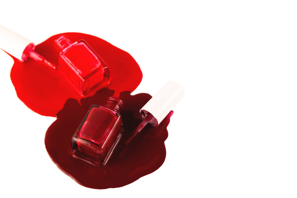 İki klasik kırmızı tırnak cilası. Dökülmüş ürünlerle birlikte açık şişeler. - Fotoğraf, Görsel