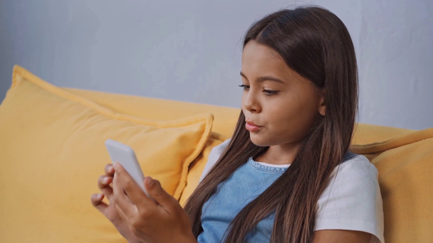 κορίτσι κάθεται στον καναπέ και χρησιμοποιώντας το smartphone  - Πλάνα, βίντεο