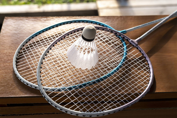Badminton rackets and shuttlecock lie on the table in the garden - 写真・画像