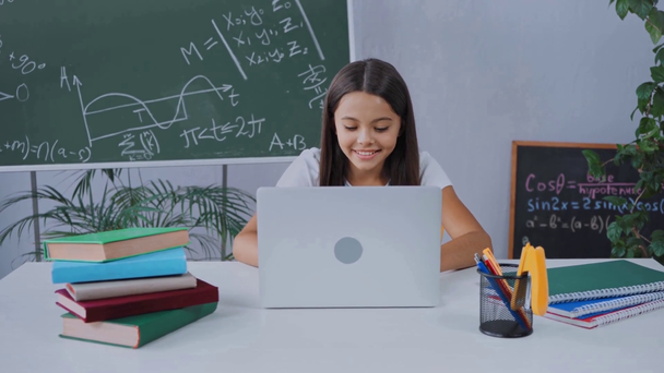 menina usando laptop e sentado na mesa enquanto estuda on-line em casa - Filmagem, Vídeo
