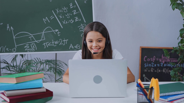 Schulmädchen im Kopfhörer hat Videochat, während sie zu Hause online lernt - Filmmaterial, Video
