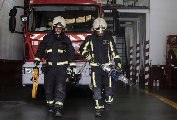 πυροσβέστες που εγκαταλείπουν τον σταθμό εξοπλισμένοι και με τα εργαλεία για την κατάσβεση της πυρκαγιάς - Φωτογραφία, εικόνα
