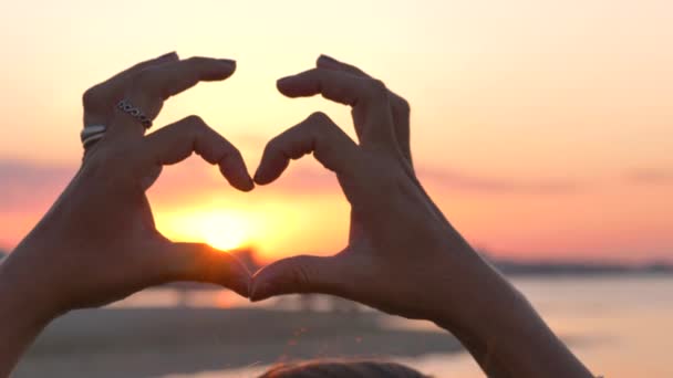 Manos de silueta haciendo una forma de corazón ay puesta de sol - Imágenes, Vídeo