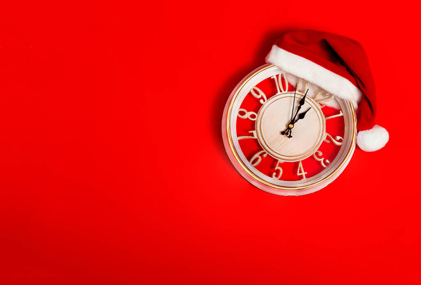  reloj sobre un fondo rojo en un sombrero de Santa Claus, año nuevo, Navidad, fondo de pantalla, horizontal - Foto, Imagen