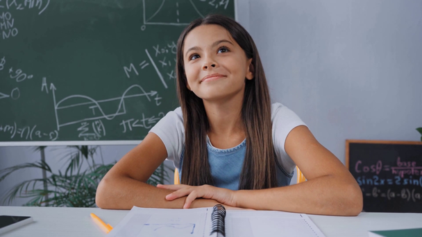 pleased child sitting and desk near chalkboard  - Materiaali, video