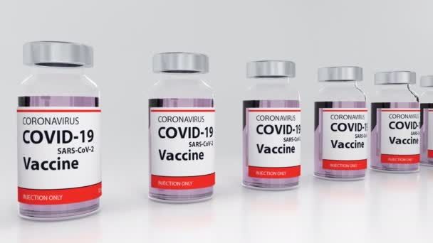 Ampolas com vacina contra o coronavírus na linha contra a alça branca de fundo - Filmagem, Vídeo