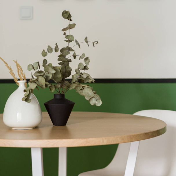 Close-up on round and wooden dining table with stylish vases and plants - Foto, immagini