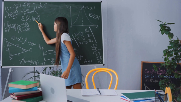 kid holding pen while showing math formulas on chalkboard  - Footage, Video