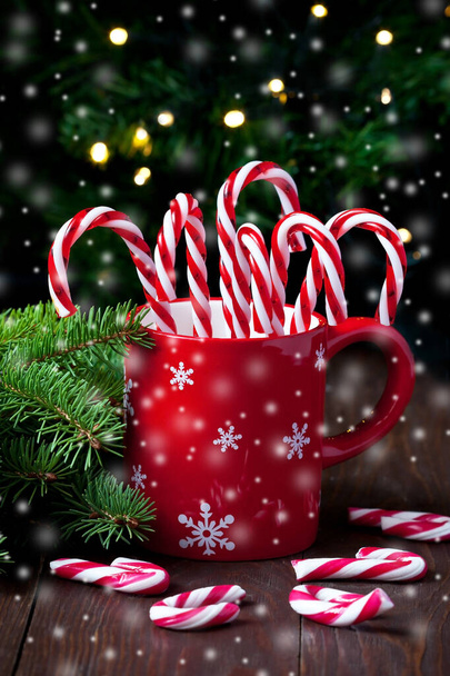 Red mug with colorful candy canes for Christmas treats, selective focus with shallow depth of field - Photo, Image