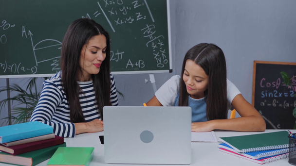 Schulkind zeigt Notizbuch mit Mathe-Grafik in der Nähe von Laptop und Mutter - Filmmaterial, Video