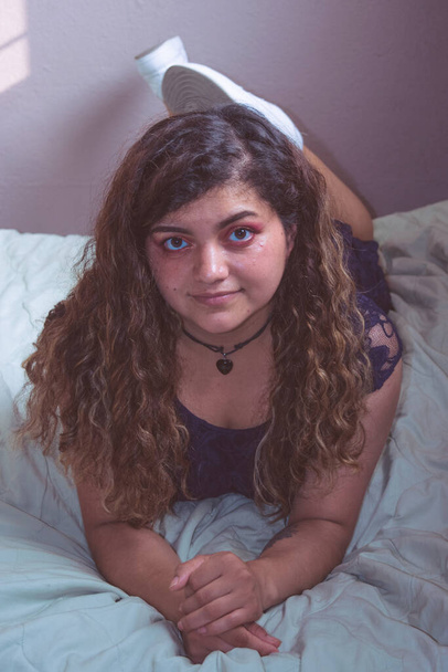 Портрет латинской женщины, лежащей на кровати и смотрящей в камеру - Фото, изображение