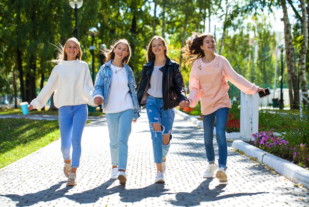Four happy young girls walking in autumn park - Photo, Image