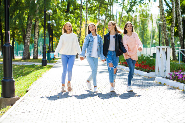 Four happy young girls walking in autumn park - 写真・画像