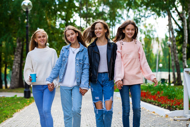Four happy teenagers girls walking in autumn park   - Фото, зображення