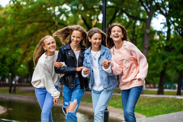Four happy teenagers girls walking in autumn park   - Foto, imagen