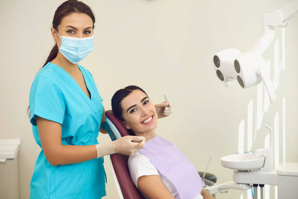 Portrait of a friendly smiling female dentist with a patient in the office of a dental clinic. - Фото, зображення