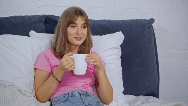 jonge vrouw met kopje koffie, klikken op kanalen en het kijken naar film - Video