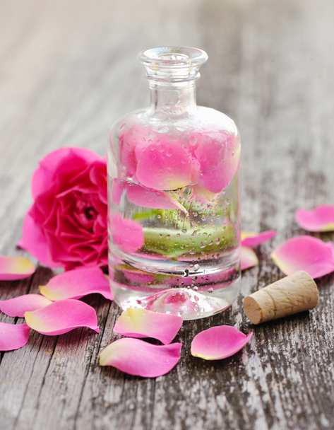 Essential oil with rose petals on wooden background - Photo, Image