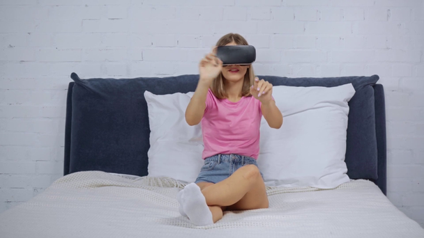 женщина в наушниках виртуальной реальности жестикулирует в спальне  - Кадры, видео