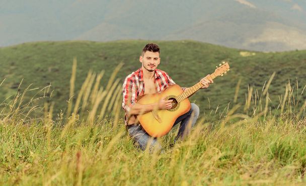 Cause the streets are singing. country music song. sexy man with guitar in checkered shirt. hipster fashion. western camping and hiking. happy and free. cowboy man with acoustic guitar player - Фото, зображення