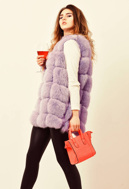 Elite fashion clothes. Designer clothing luxury fashion boutique. Woman with handbag hold glass of wine. Girl wear fashion fur vest while posing with bag. Luxury store concept. Lady likes shopping - Foto, imagen