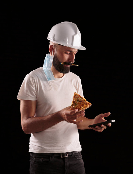 Jeune travailleur hispanique de la construction masculine vérifiant son téléphone pendant le déjeuner - Photo, image