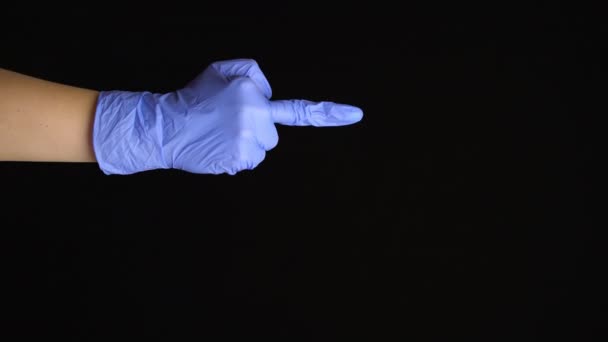 Female hand in a latex medical glove makes an middle finger gesture isolated on black background - Footage, Video