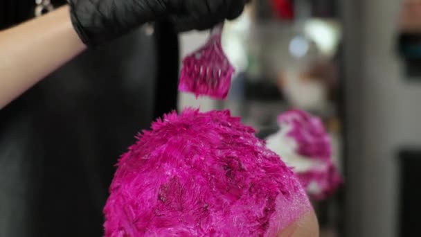 De kapper verft de vrouwen haar roze. Huis salon tijdens de epidemie. LGBT Met een masker op mijn gezicht. - Video