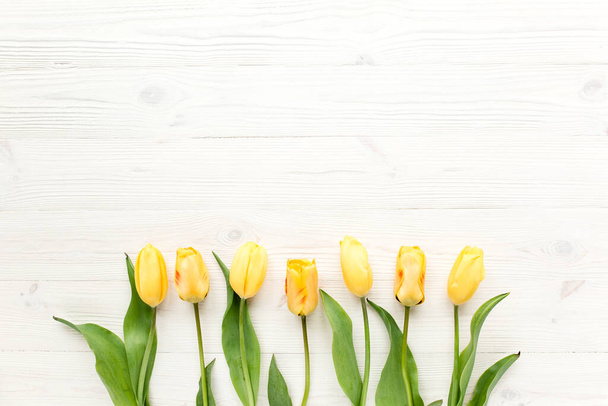 yellow tulips isolated on a white, wooden background. lay flat, top view - Fotoğraf, Görsel