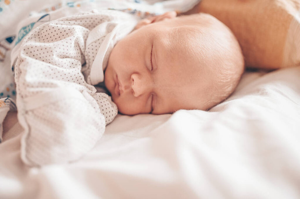 Aranyos, érzelmes, vicces, újszülött kisfiú, aki bölcsőben alszik. Babaáru csomagolási sablon. Egészséges gyermek, a kórház és a boldog anyaság fogalma. Csecsemő. Gyermekszoba. - Fotó, kép
