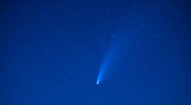 夜空に輝く青い星空の中で、彗星や流れ星の痕跡。天文学やクリスマスの背景. - 写真・画像