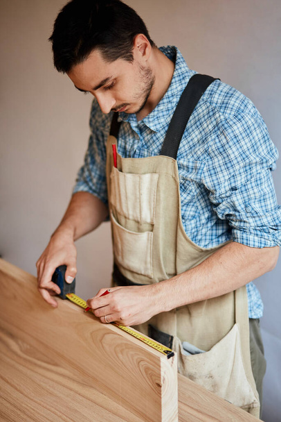 hand of a carpenter taking measurement of a wooden plank - Foto, Bild