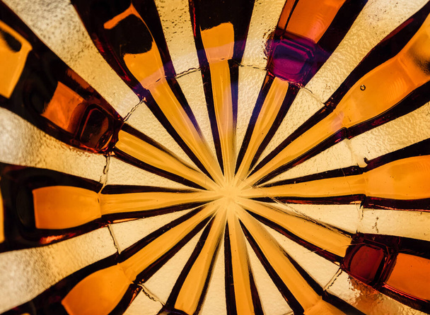 Värillinen lasi kuviollinen tausta. Kaunis, keltainen, oranssi, viininpunainen, ruskea värillinen lasi säteittäinen kuvio täyttää kehyksen. - Valokuva, kuva