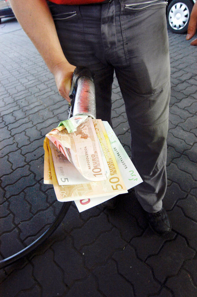 holding tank nozzle with banknotes in the hand, fuel costs at the gas station - Photo, Image