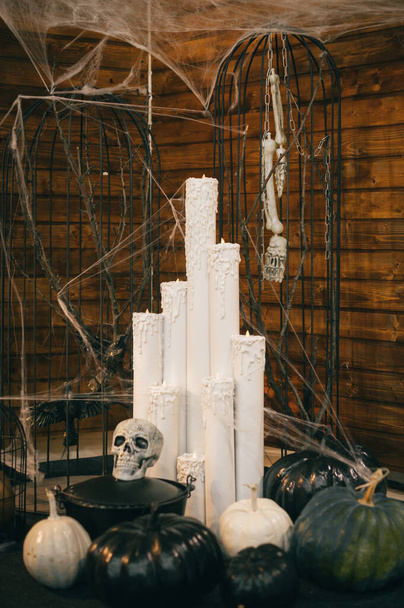 Foto de decoraciones para Halloween. Velas, una jaula con huesos, calabazas y un cráneo. Vertical. Decoración de Halloween. - Foto, Imagen