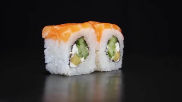 Los rollos de sushi giran sobre fondo negro. Dispara de cerca. Filadelfia queso y salmón en la comida japonesa. - Metraje, vídeo