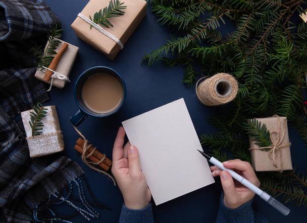  Руки девушки, пишущей рождественский список на синем фоне - Фото, изображение